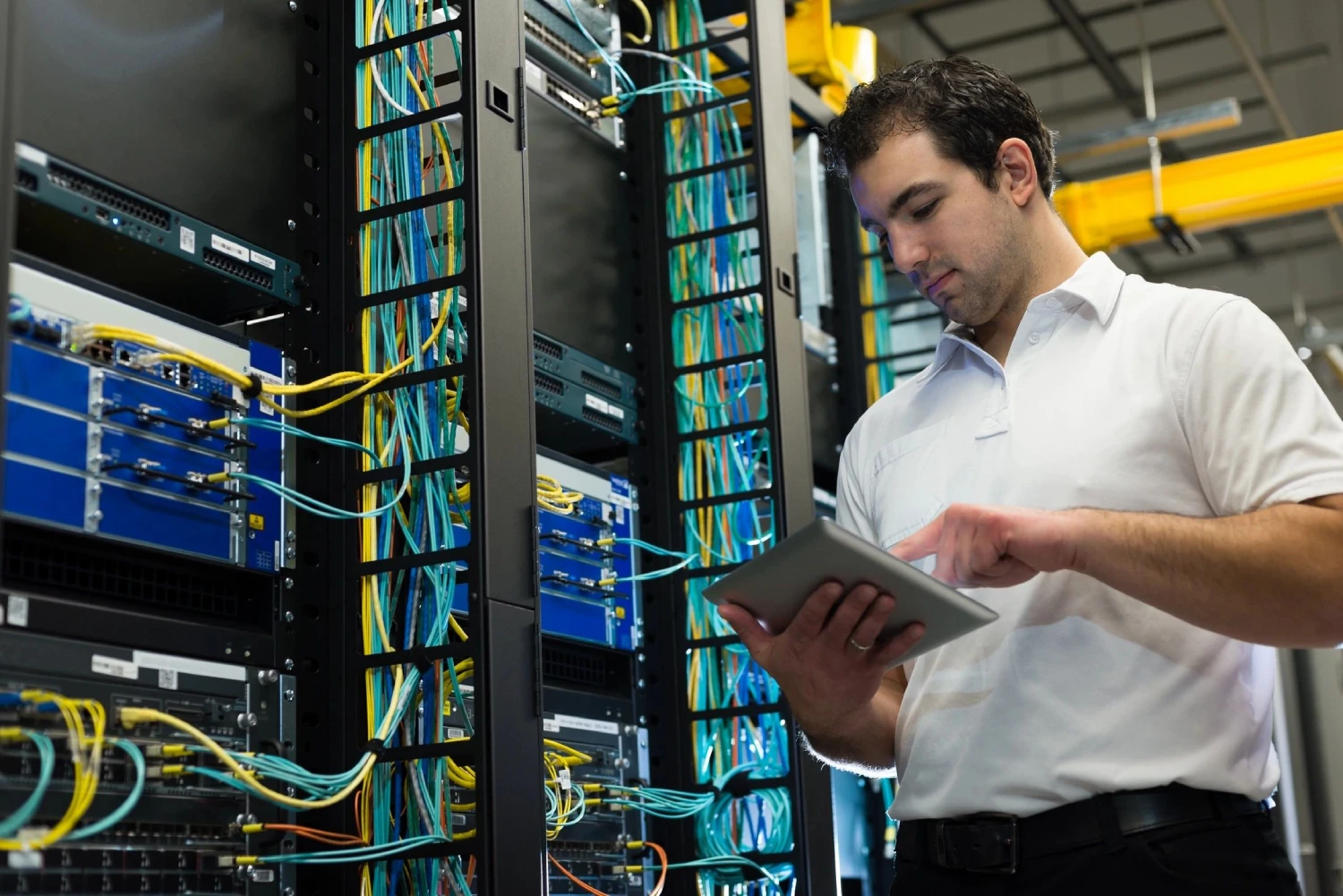 a person holding a tablet in front of a server room